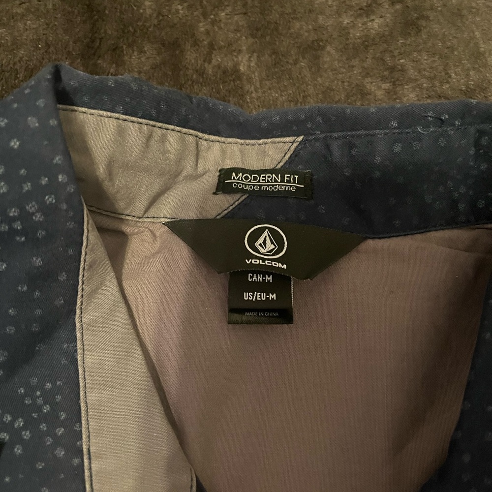 This is a medium-sized navy blue Volcom button-up shirt for men